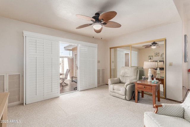 living area featuring carpet flooring and a ceiling fan