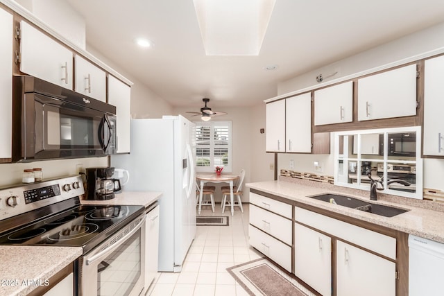 kitchen featuring electric stove, black microwave, white dishwasher, and a sink