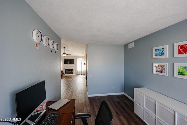 office area with ceiling fan, dark hardwood / wood-style floors, and a textured ceiling