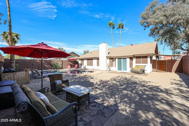 rear view of house with outdoor lounge area, a fenced in pool, and a patio