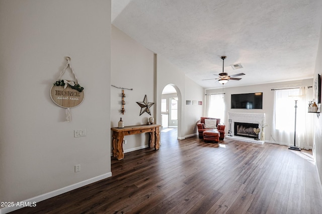 unfurnished living room featuring ceiling fan, a textured ceiling, a fireplace, and dark hardwood / wood-style flooring