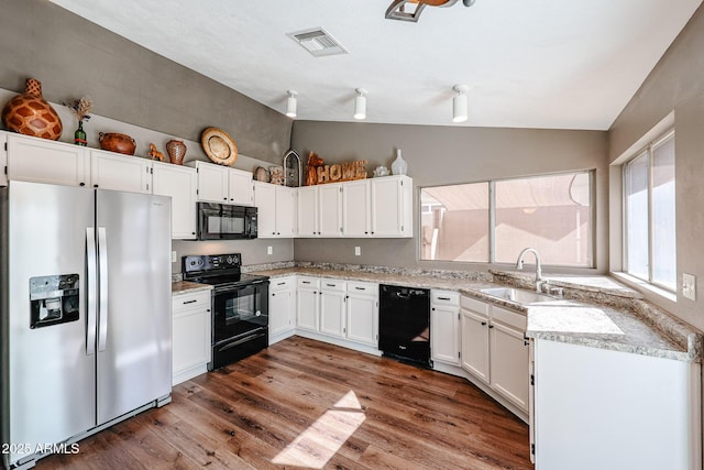 kitchen featuring sink, vaulted ceiling, black appliances, and white cabinets