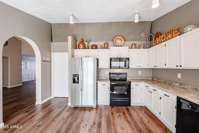 kitchen with white cabinetry, lofted ceiling, and black appliances