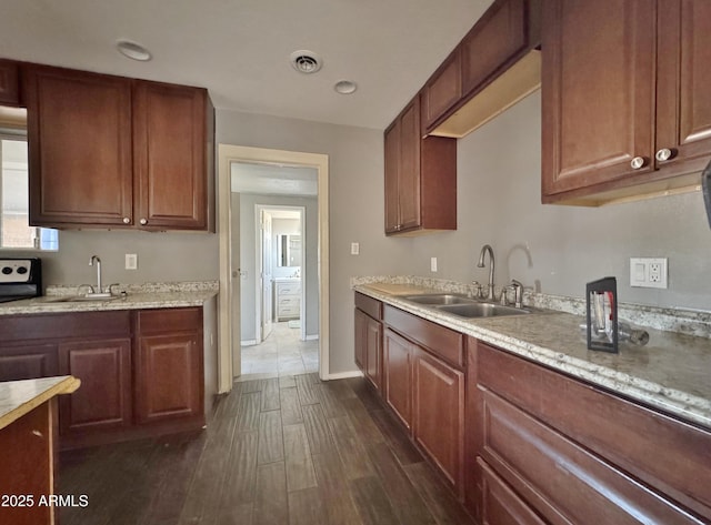 kitchen featuring light stone counters, dark hardwood / wood-style flooring, and sink