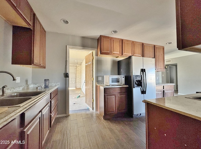 kitchen featuring hardwood / wood-style flooring, stainless steel refrigerator with ice dispenser, and sink