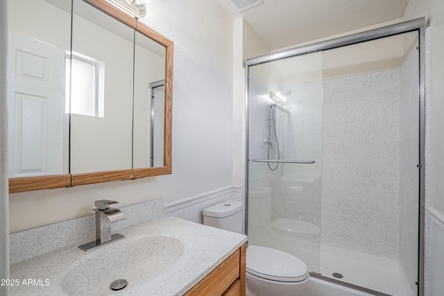 bathroom featuring a shower with door, vanity, and toilet