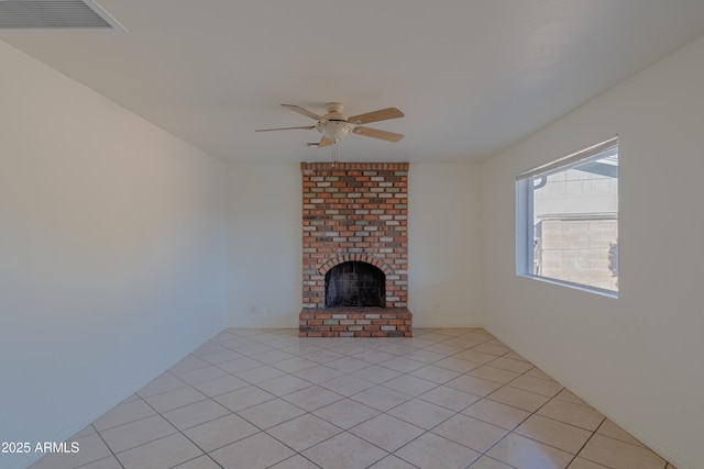 unfurnished living room featuring a brick fireplace, ceiling fan, and light tile patterned flooring