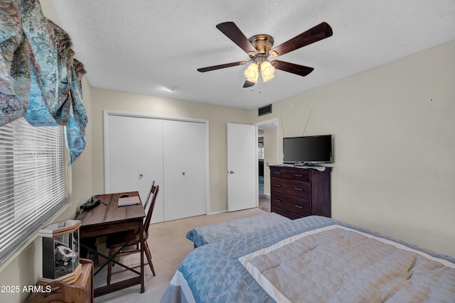 bedroom with visible vents, a textured ceiling, a closet, light colored carpet, and ceiling fan