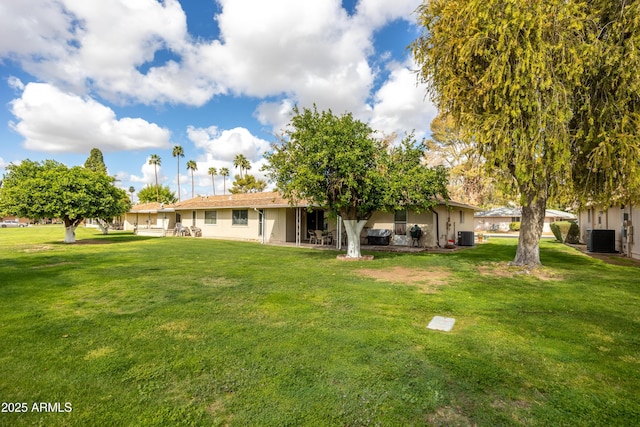 back of property featuring a lawn, central AC, and stucco siding