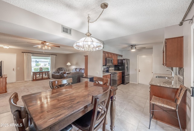 dining space with visible vents, ceiling fan with notable chandelier, and a textured ceiling