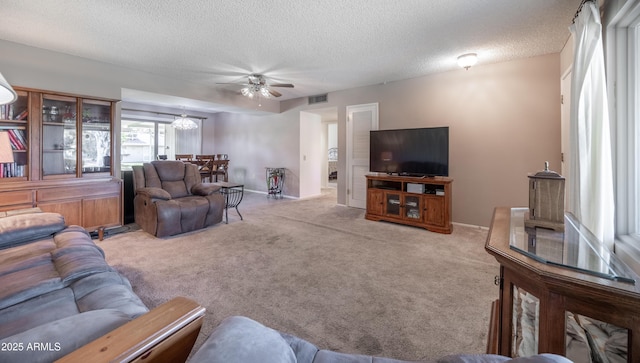 carpeted living area with baseboards, visible vents, a textured ceiling, and ceiling fan