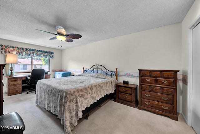 bedroom featuring light colored carpet, a textured ceiling, and ceiling fan