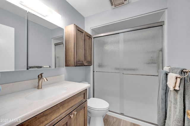 bathroom with vanity, wood finished floors, visible vents, a stall shower, and toilet