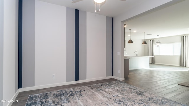 spare room with a sink, baseboards, a ceiling fan, and wood finished floors