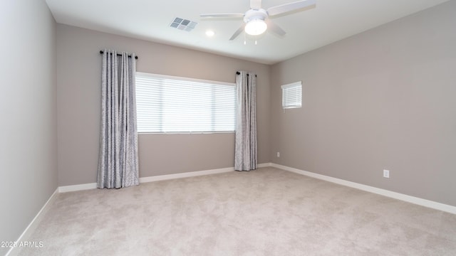 carpeted spare room with plenty of natural light, baseboards, ceiling fan, and visible vents