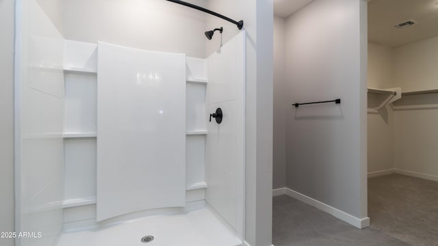 bathroom with walk in shower, baseboards, visible vents, and a walk in closet