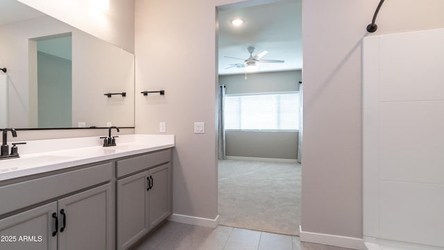 full bath featuring baseboards, double vanity, ceiling fan, and a sink