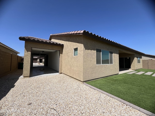 rear view of house with a lawn, a patio, fence, and stucco siding