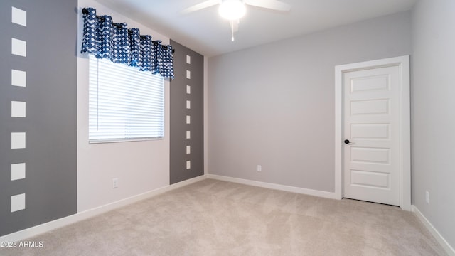 unfurnished room featuring ceiling fan, light colored carpet, and baseboards