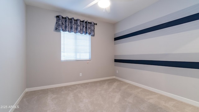 spare room with ceiling fan, light carpet, and baseboards