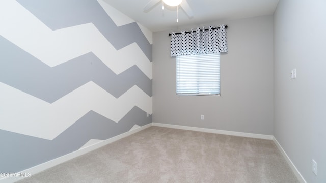 carpeted spare room with a ceiling fan and baseboards