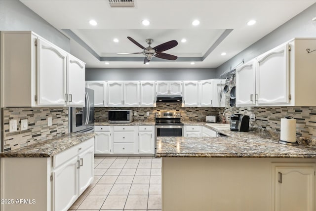 kitchen with sink, a tray ceiling, kitchen peninsula, and appliances with stainless steel finishes