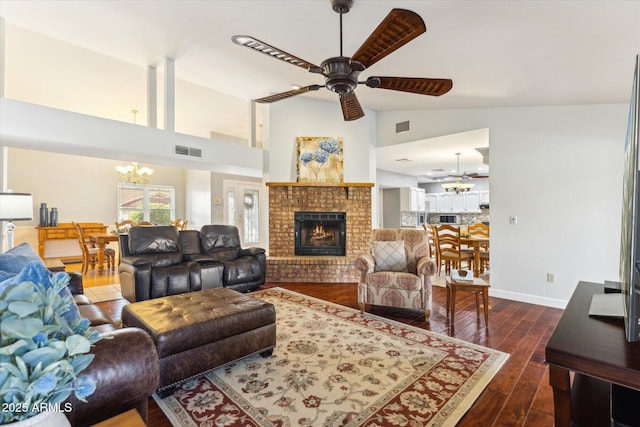 living room featuring a brick fireplace, dark wood-type flooring, ceiling fan with notable chandelier, and high vaulted ceiling