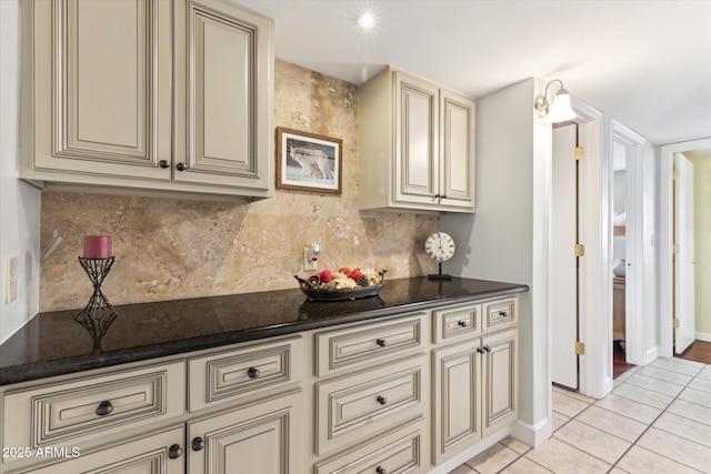 kitchen with cream cabinets, dark stone countertops, and light tile patterned floors