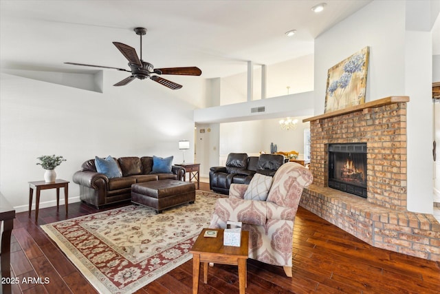 living room with high vaulted ceiling, ceiling fan with notable chandelier, dark hardwood / wood-style flooring, and a brick fireplace