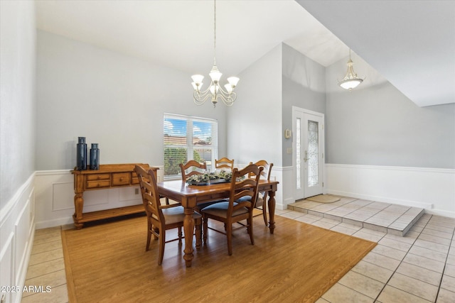 dining area featuring a notable chandelier, vaulted ceiling, and light tile patterned floors