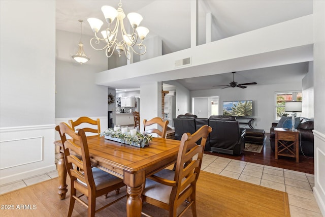 dining area featuring vaulted ceiling, ceiling fan with notable chandelier, and light tile patterned floors