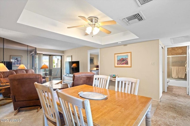 dining space with a tray ceiling and ceiling fan