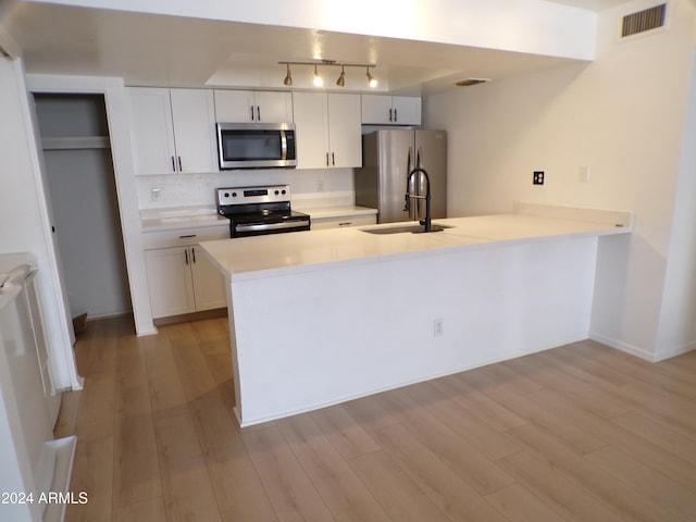 kitchen with kitchen peninsula, light wood-type flooring, stainless steel appliances, sink, and white cabinetry