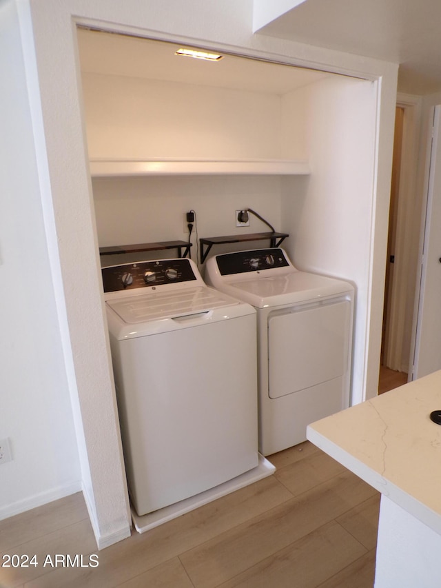 laundry room with washing machine and dryer and light hardwood / wood-style floors