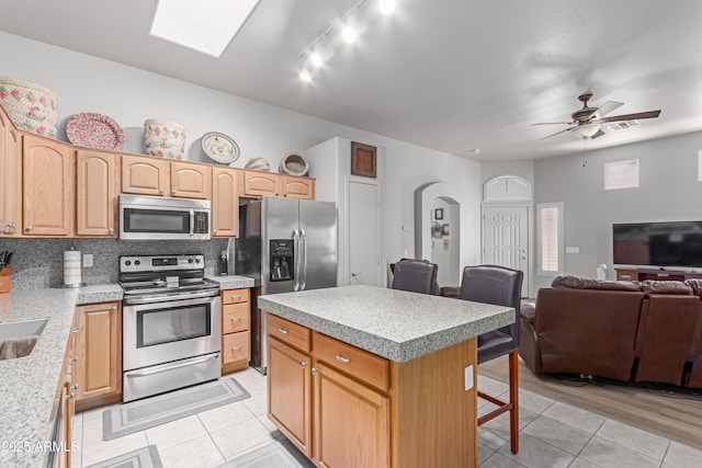 6610 E University Dr Unit 2, Mesa, AZ 85205 - kitchen with stainless steel appliances, a kitchen bar, light tile patterned floors, open floor plan, and arched walkways