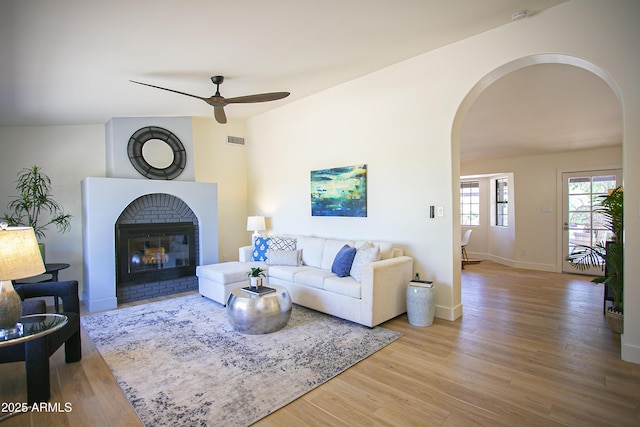 6608 E Ranch Rd, Cave Creek, AZ 85331 - living room with arched walkways, ceiling fan, wood finished floors, and a fireplace