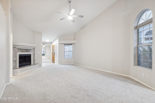 unfurnished living room with ceiling fan, a fireplace, light carpet, and high vaulted ceiling