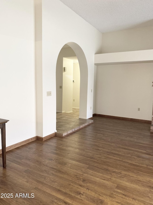 1249 E Commerce Ave, Gilbert, AZ 85234 - empty room featuring dark wood-style floors, a textured ceiling, and arched walkways