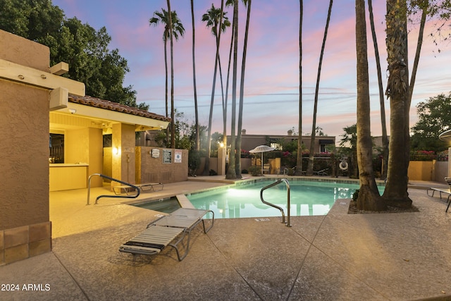 pool at dusk with a patio area