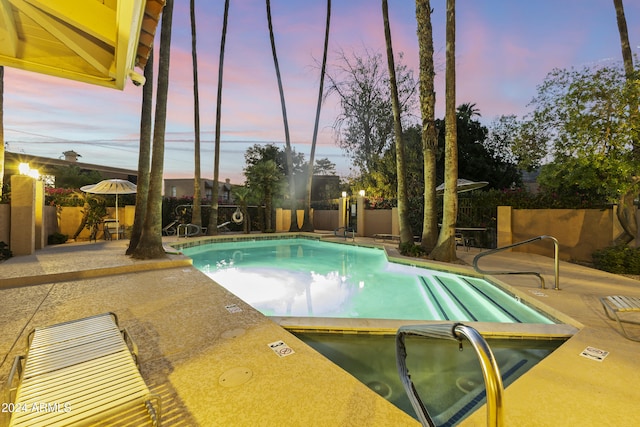 pool at dusk with a patio area