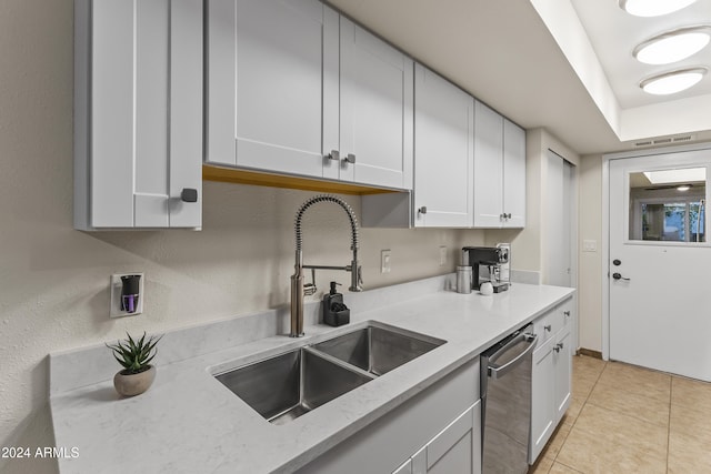 kitchen featuring stainless steel dishwasher, sink, white cabinets, and light stone counters