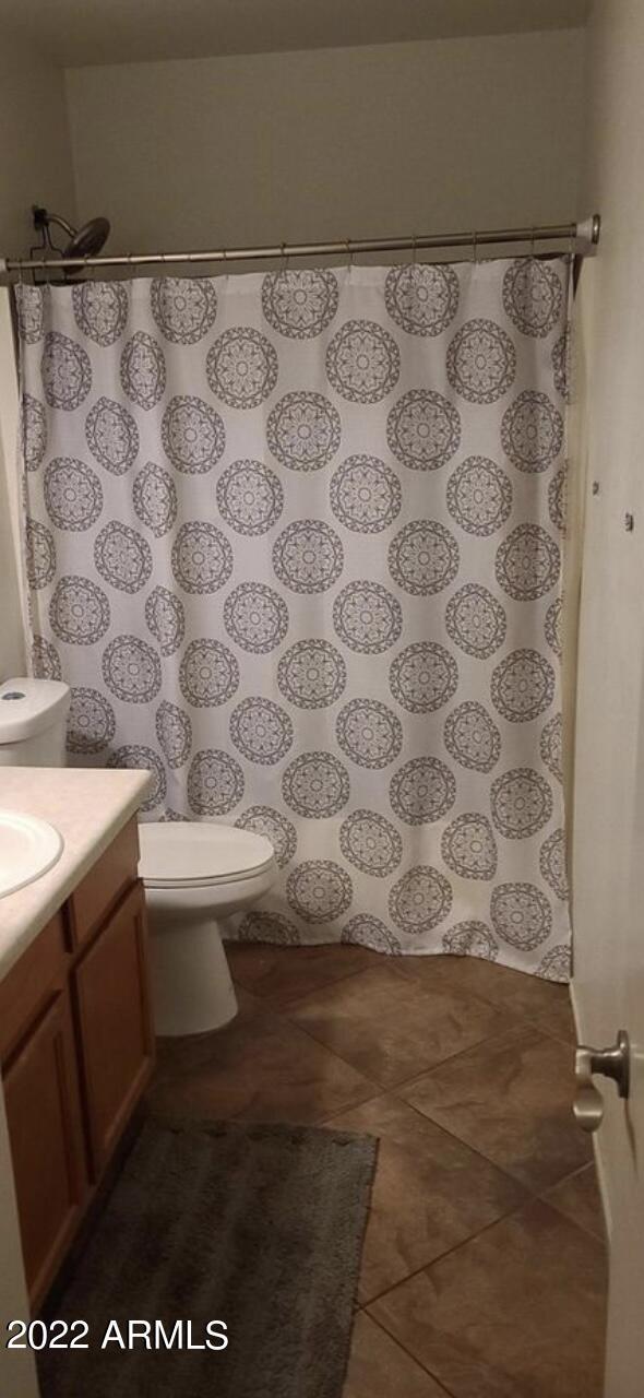 bathroom with vanity, toilet, curtained shower, and tile patterned flooring