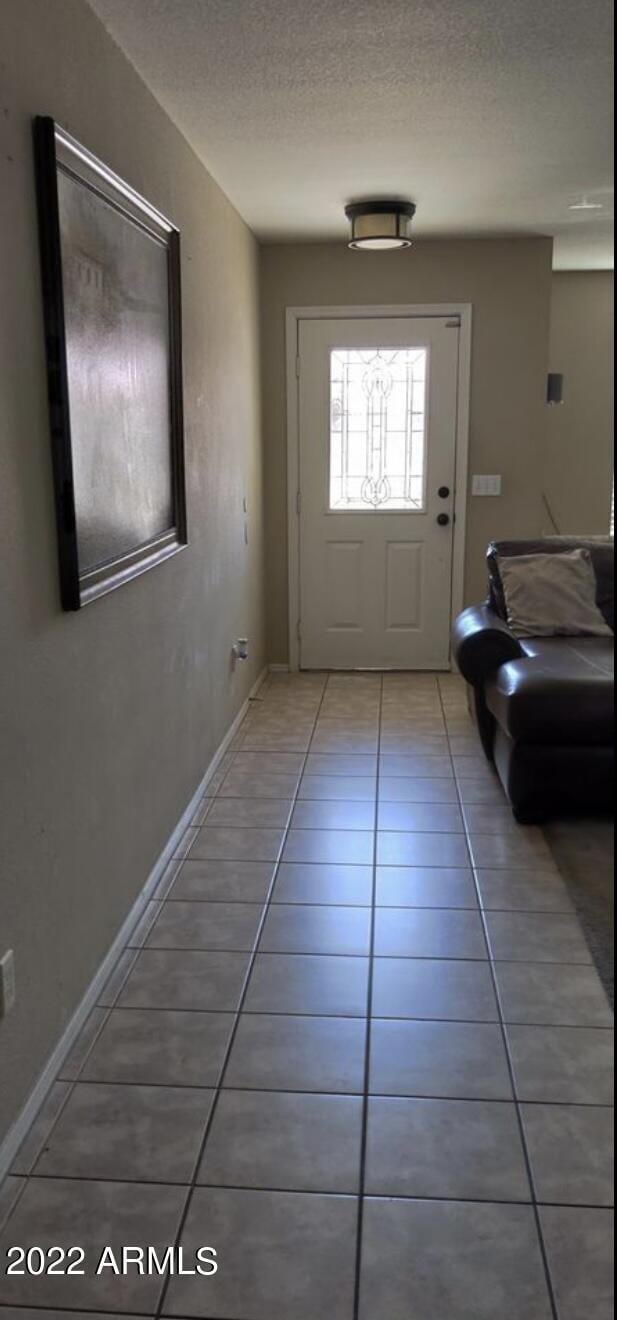 doorway to outside featuring tile patterned floors and a textured ceiling