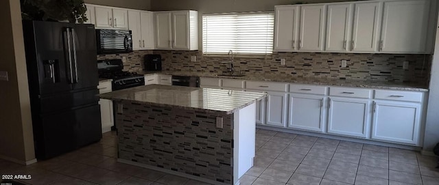 kitchen featuring white cabinets, light stone countertops, light tile patterned floors, and black appliances