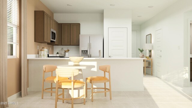 23356 W Atlanta Ave, Buckeye, AZ 85326 - kitchen with a breakfast bar area, a peninsula, white refrigerator with ice dispenser, and light tile patterned floors