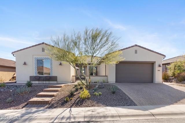 mediterranean / spanish home featuring a garage, decorative driveway, a tile roof, and stucco siding