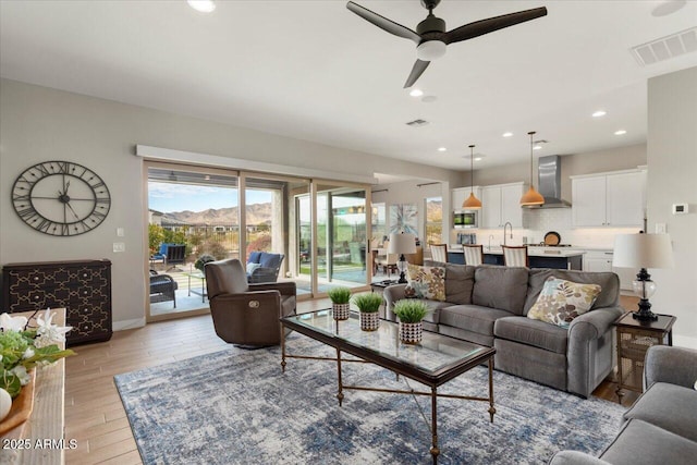 living room with ceiling fan, sink, and light hardwood / wood-style floors