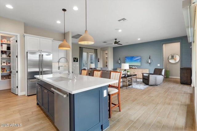 kitchen featuring pendant lighting, white cabinets, stainless steel appliances, sink, and ceiling fan