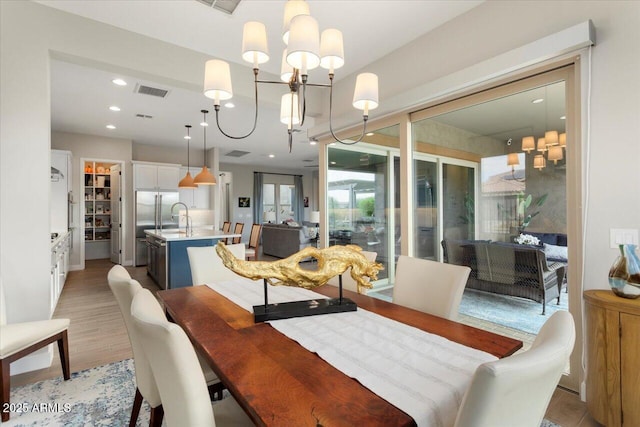 dining room featuring an inviting chandelier, light hardwood / wood-style flooring, and sink