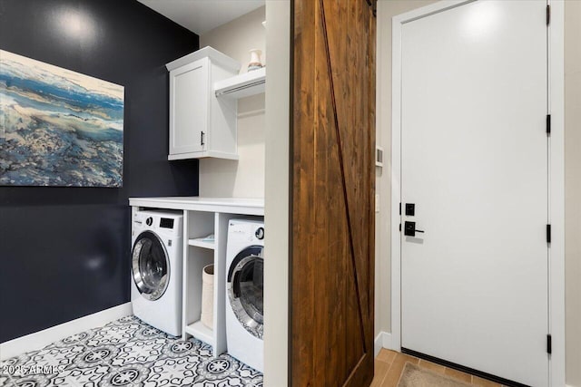 laundry area featuring cabinets, washing machine and dryer, and a barn door